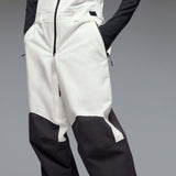 MTimberlineShellBib-A white and black technical snow bib with adjustable shoulder straps, a front zipper, and reinforced lower leg panels, shown against a neutral gray gradient background.