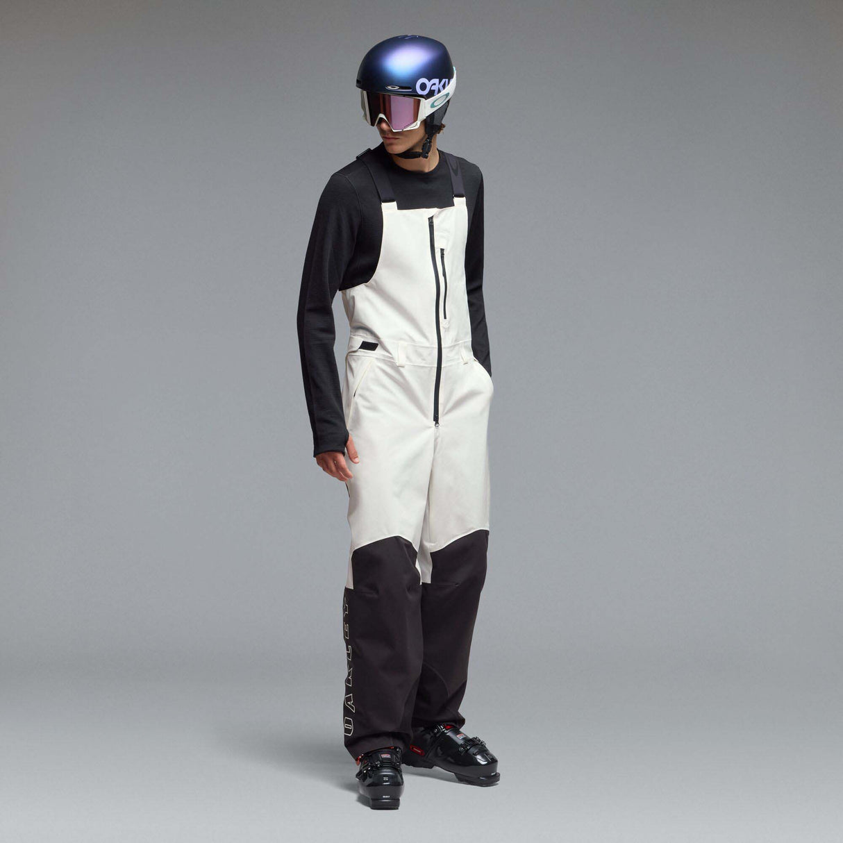 MTimberlineShellBib-A white and black technical snow bib with adjustable shoulder straps, a front zipper, and reinforced lower leg panels, shown against a neutral gray gradient background.