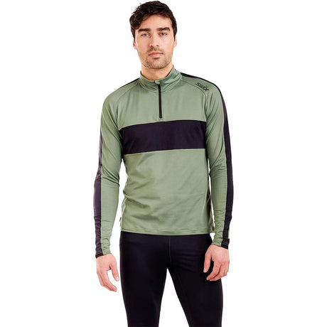 MTista1_2ZipMidlayer- A man wearing a sage green and black long-sleeve quarter-zip athletic pullover, paired with black pants, against a plain white background.