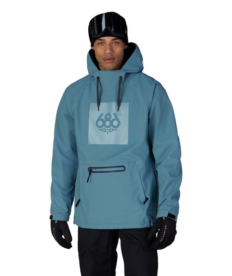MWaterproofHoody-A man wearing a light blue hooded snowboard jacket with a large square 686 brand logo on the chest, black gloves, and a black beanie with goggles, set against a plain white background.