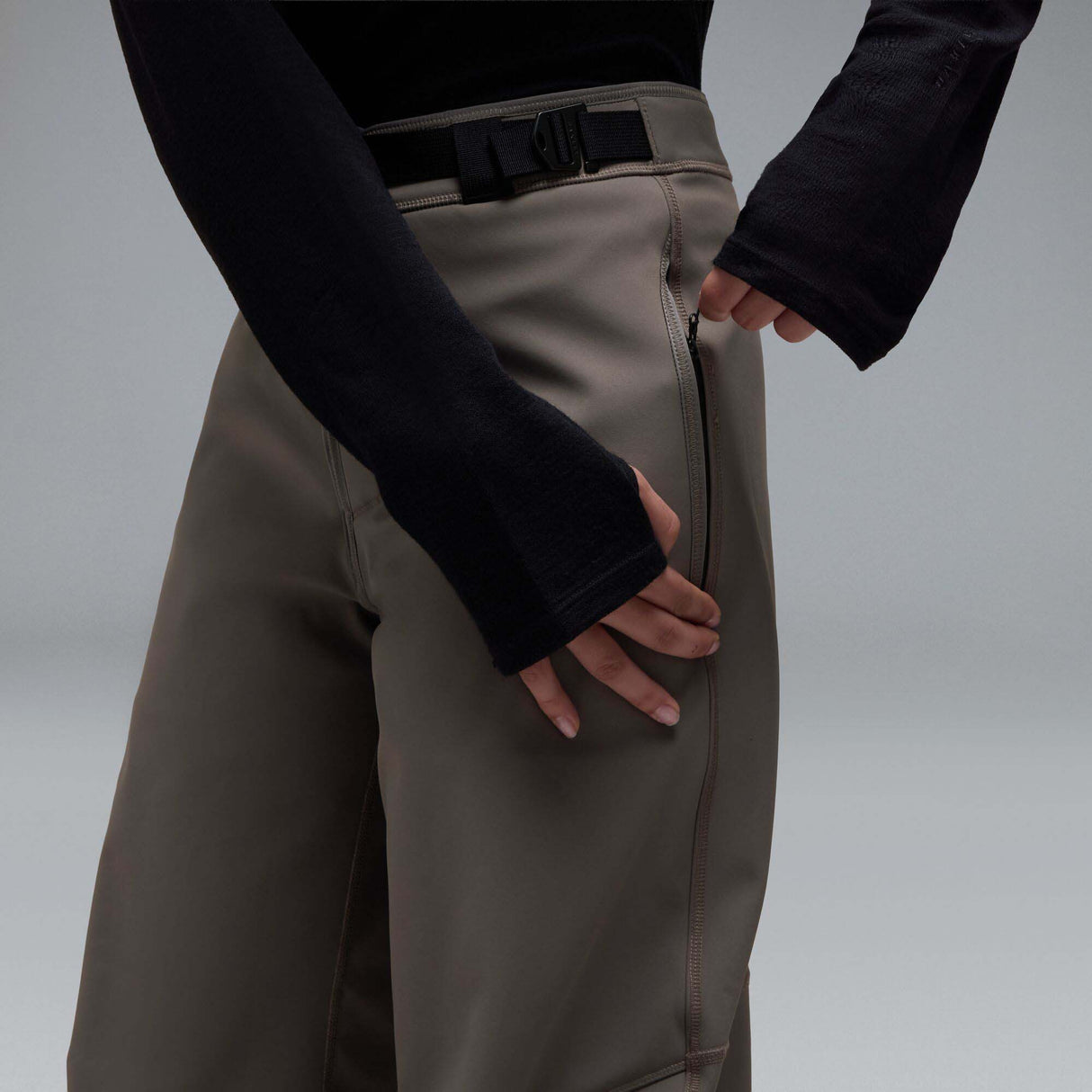 MWintertideSoftshellPant-A pair of gray snow pants with a black belt and a small black Oakley logo on the left thigh, displayed against a neutral gray gradient background.