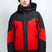 OrionMensInsulatedJacket-A man wearing a red and black Karbon ski jacket, a green knit beanie, and ski goggles, standing against a light gray studio background.