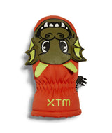PuppetMitt-A pair of bright orange children's winter mittens shown flat against a white background. One mitten displays a green cartoon monster face with yellow accents, and the other shows the back with black elasticized wrist panels and a small black brand tag.