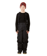 ScoobieIIPant-A child model wearing black snow bib overalls with suspenders, a black long-sleeve shirt, black snow boots, and a burgundy knit beanie, standing against a solid white background.