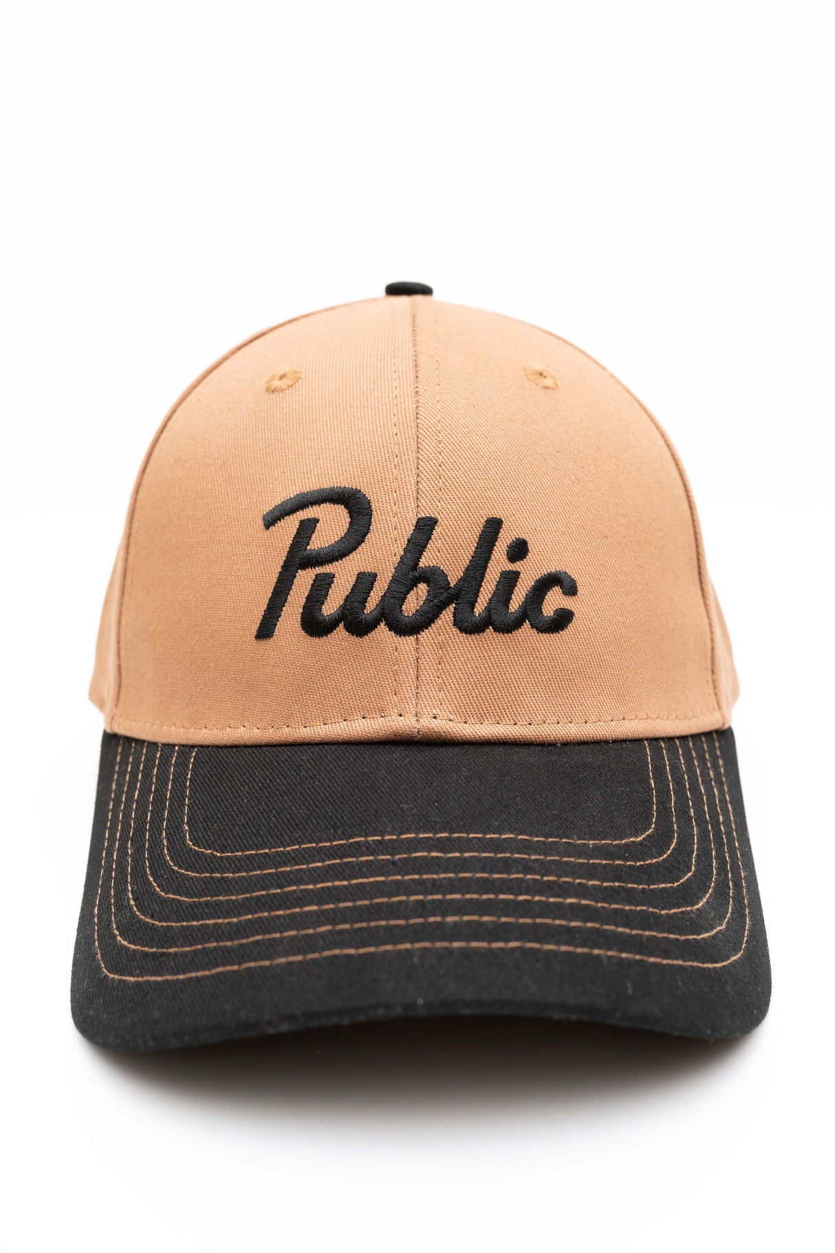 ScriptCap-A two-tone baseball cap with a tan crown and a dark charcoal gray brim, featuring the word 'Public' embroidered in black script across the front.