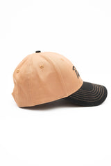ScriptCap-A two-tone baseball cap with a tan crown and a dark charcoal gray brim, featuring the word 'Public' embroidered in black script across the front.