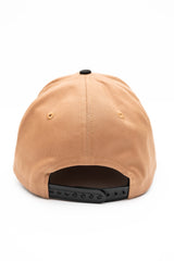ScriptCap-A two-tone baseball cap with a tan crown and a dark charcoal gray brim, featuring the word 'Public' embroidered in black script across the front.