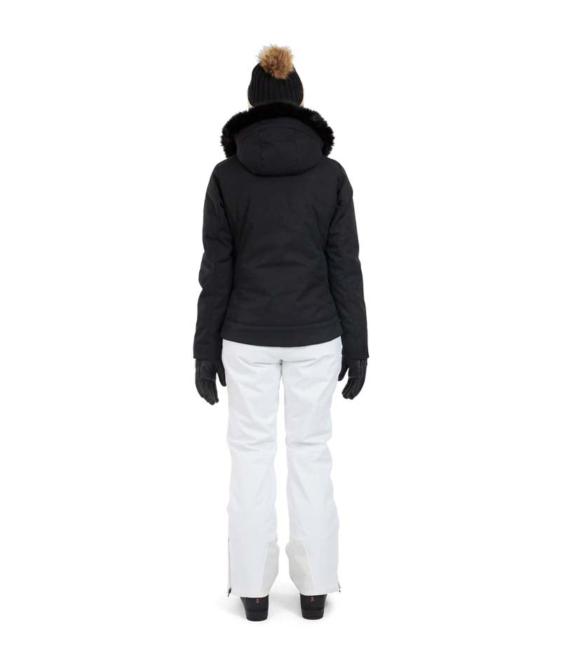 SolaceJacket-A woman wearing a black ski jacket with a faux-fur trimmed hood, black gloves, a black beanie, and ski goggles, posed against a solid white background.
