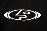 StretchLogoHoody-Close-up of a black garment featuring a large white circular logo with stylized lettering across the chest, centered around the zipper.