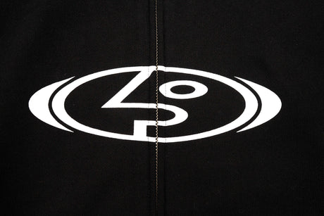 StretchLogoHoody-Close-up of a black garment featuring a large white circular logo with stylized lettering across the chest, centered around the zipper.