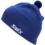 TraditionBeanie-A royal blue knit beanie hat with a white embroidered 'Swix' logo on the front and a matching blue pom-pom on top, shown against a plain white background.