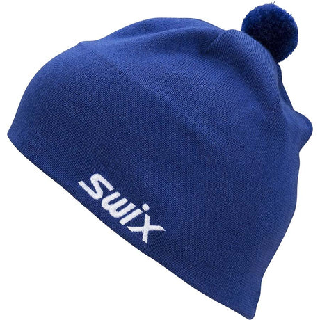 TraditionBeanie-A royal blue knit beanie hat with a white embroidered 'Swix' logo on the front and a matching blue pom-pom on top, shown against a plain white background.