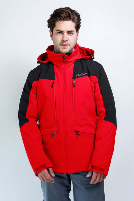 TritonMensInsulatedJacket-A man wearing a red and black Karbon hooded jacket, standing against a light gray studio background.
