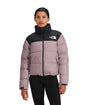W1996RetroNuptseJacket-Person wearing a pink and black jacket with The North Face logo on a white background