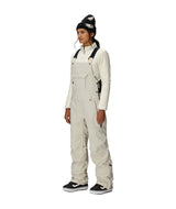 WBlackMagicInsulatedBib-Person wearing a white snowsuit and black beanie on a white background