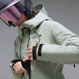 WCanopyInsulatedJacket-A light sage green hooded jacket with black zipper and drawstring details, displayed on a neutral gray background. The Oakley logo is visible on the left chest.