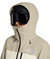 WFreedomInsulatedJacket-Person wearing a beige The North Face jacket with a black helmet and goggles on a white background