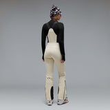 WIcicleSoftshellBib-A pair of ski bib pants in off-white with black suspenders, black zipper details, and black paneling at the lower legs, shown against a neutral gray gradient background.