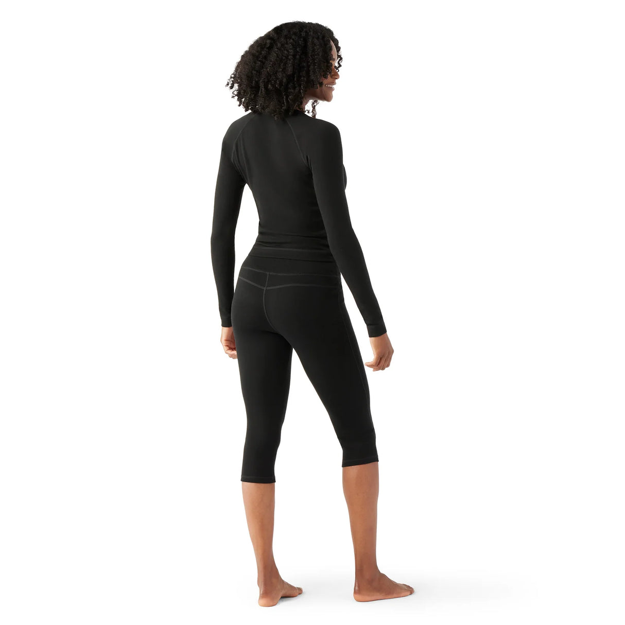 WMerinoBaselayer3_4Pant-Person wearing black long-sleeve top and capri leggings on a white background