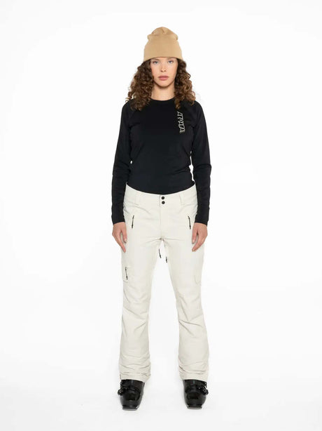 WMula2LInsulatedPant-Woman wearing a black top and white pants with a beige beanie on a white background