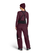WSummitVerbierGTXBib-Person wearing a maroon ski suit with suspenders on a white background