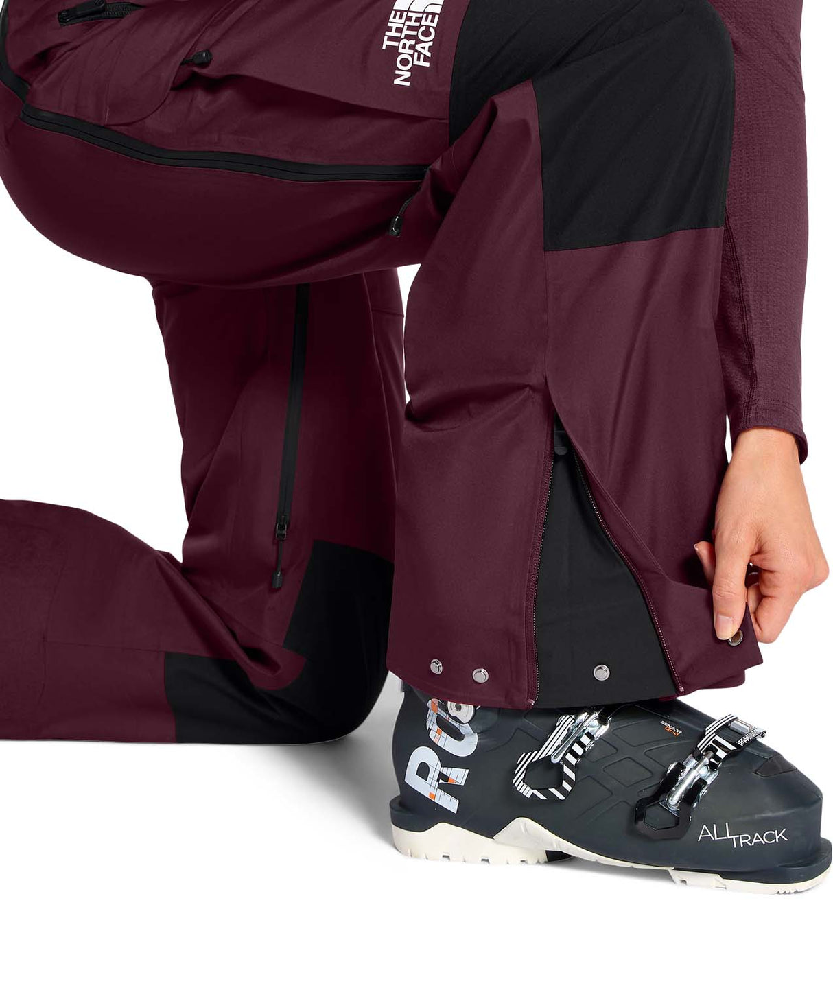 WSummitVerbierGTXBib-Person wearing maroon pants and black ski boots with visible branding on a white background
