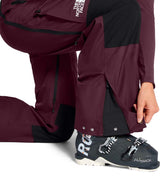 WSummitVerbierGTXBib-Person wearing maroon pants and black ski boots with visible branding on a white background