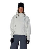 WWaterproofTeamCropHoody-Person wearing a light gray jacket, black beanie, and dark pants on a white background