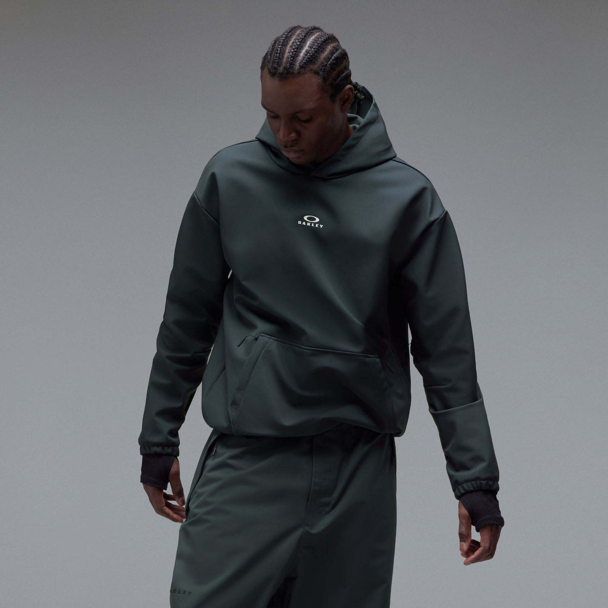 WintertideScratchedHoodie-A dark charcoal gray hooded sweatshirt with a small white Oakley logo on the left chest, displayed against a neutral gray gradient background.