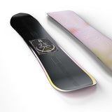 Wonder- Black snowboard with a multi colored design in the center with a light pink and yellow base shown on a white background