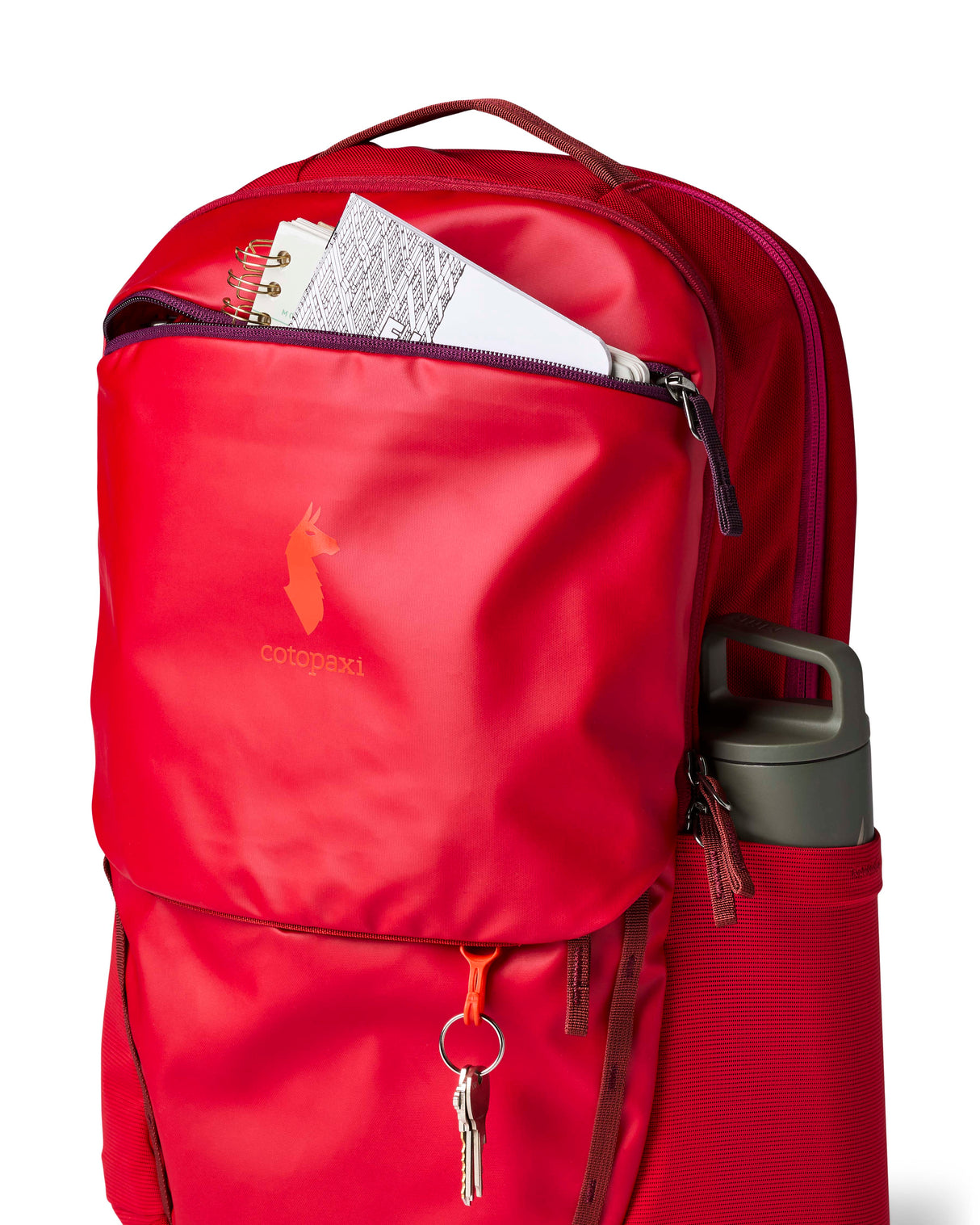allpa-26l-daypack-A red Cotopaxi backpack with a matte finish, featuring a top zippered compartment, a main compartment, and a front zippered pocket. The brand logo is printed in orange on the front center.