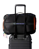 allpa-35l-travel-pack-A black Cotopaxi backpack with a pink llama logo on the front, accented with bright blue, purple, and multicolor zipper details, shown on a white background.
