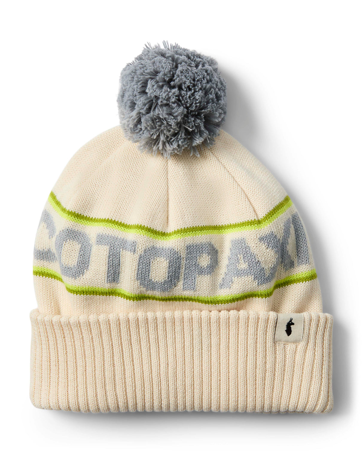 cumbre-2.0-beanie-A cream-colored knit beanie with a gray pom-pom, featuring a lime green stripe with 'COTOPAXI' knitted in gray across the middle and a ribbed cuff with a small black logo tag.