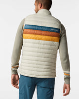 m-fuego-down-vest- A quilted puffer vest by Cotopaxi in a light beige color, featuring horizontal quilting, a full-zip front, and a mock neck collar. It has a distinctive color-blocked chest design with horizontal stripes of dark teal, rust orange, and golden yellow, with the Cotopaxi logo printed on the chest.