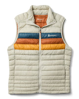 m-fuego-down-vest- A quilted puffer vest by Cotopaxi in a light beige color, featuring horizontal quilting, a full-zip front, and a mock neck collar. It has a distinctive color-blocked chest design with horizontal stripes of dark teal, rust orange, and golden yellow, with the Cotopaxi logo printed on the chest.