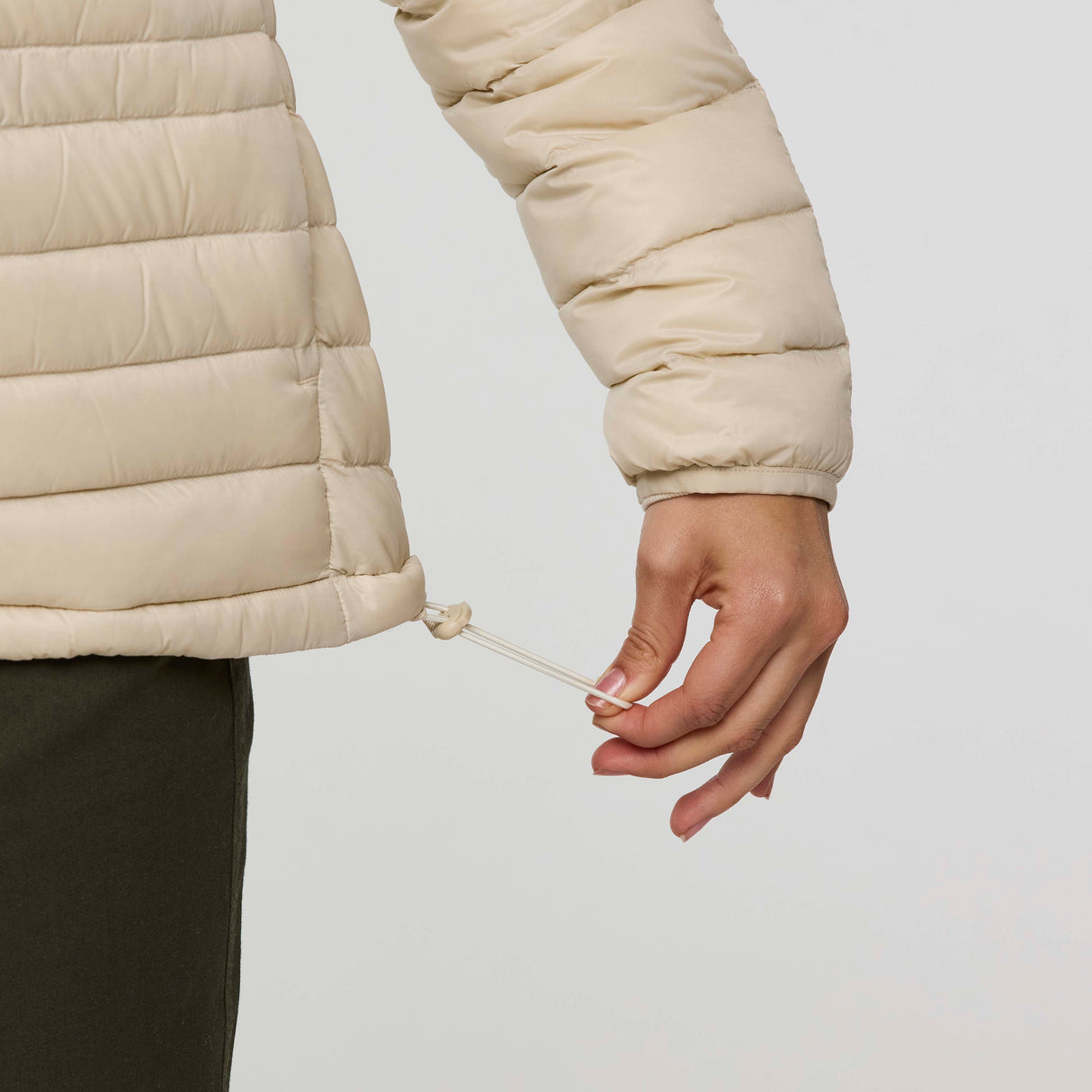 w-fuego-down-jacket- A beige quilted puffer jacket with a gray chest stripe and a visible Cotopaxi logo on the left chest, displayed against a clean white background.