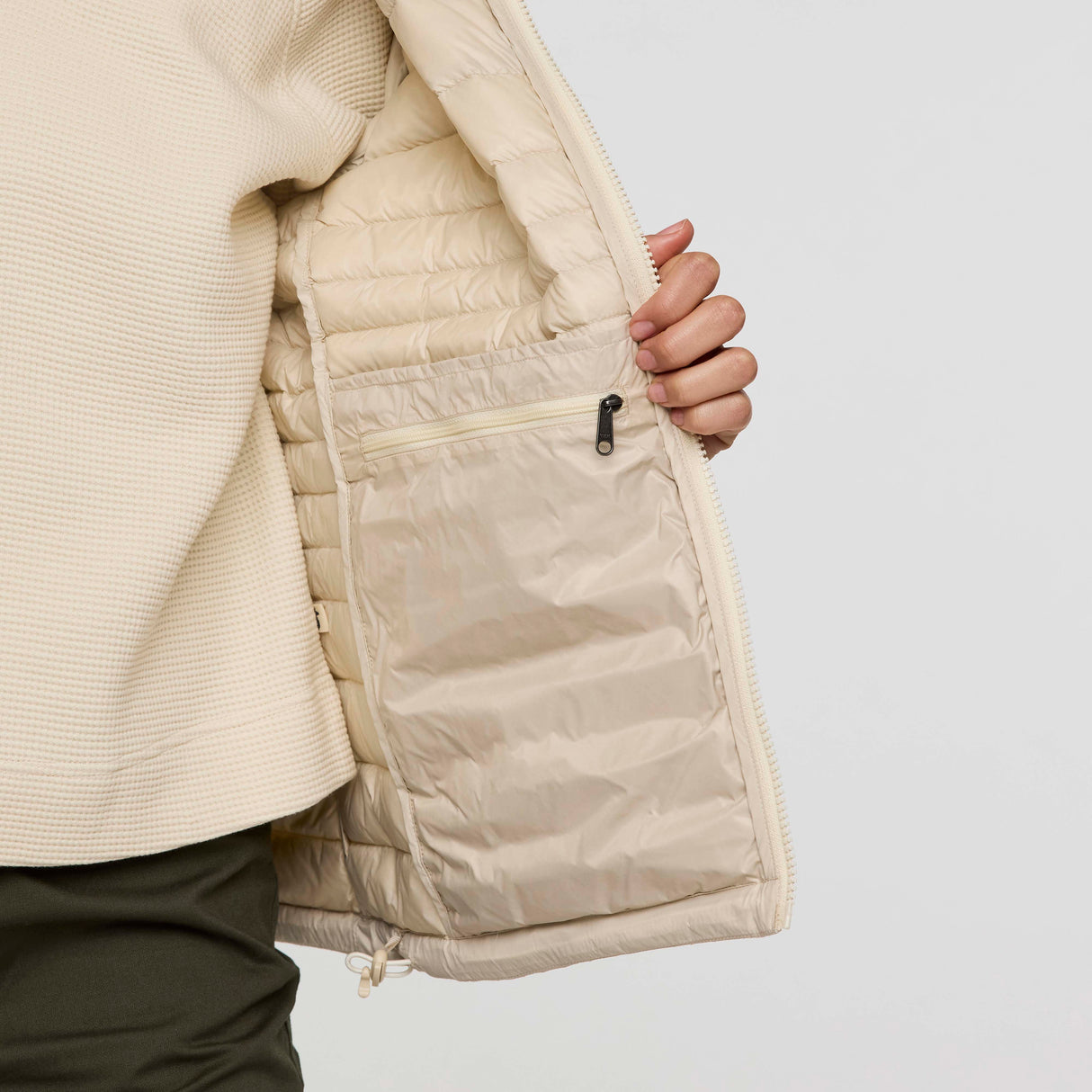 w-fuego-down-jacket- A beige quilted puffer jacket with a gray chest stripe and a visible Cotopaxi logo on the left chest, displayed against a clean white background.