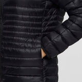w-fuego-down-parka-A woman modeling a long, black quilted puffer jacket with a hood and a small embroidered 'Cotopaxi' logo on the left chest, set against a plain light gray studio background.