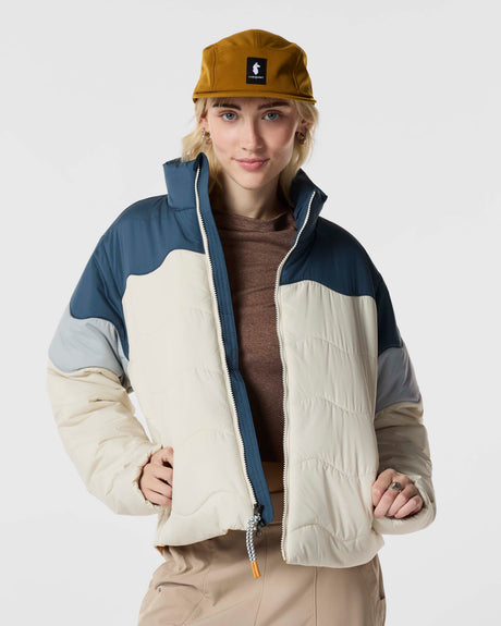 w-lumbre-insulated-jacket- A color-blocked puffer jacket, featuring an off-white body, a navy blue yoke, light gray sleeves, and a bright orange interior lining, displayed on a clean white background.